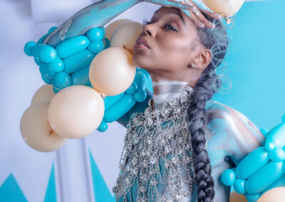 A striking fine art and fashion portrait by Victoria Machin Photography, featuring a model adorned with balloon couture, intricate body paint, and shimmering crystal embellishments. The bold Tiffany blue and champagne color palette enhances the avant-garde style of this award-winning fine art