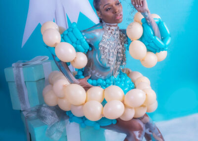 A striking fine art and fashion portrait by Victoria Machin Photography, featuring a model adorned with balloon couture, intricate body paint, and shimmering crystal embellishments. The bold Tiffany blue and champagne color palette enhances the avant-garde style of this award-winning fine art composition.