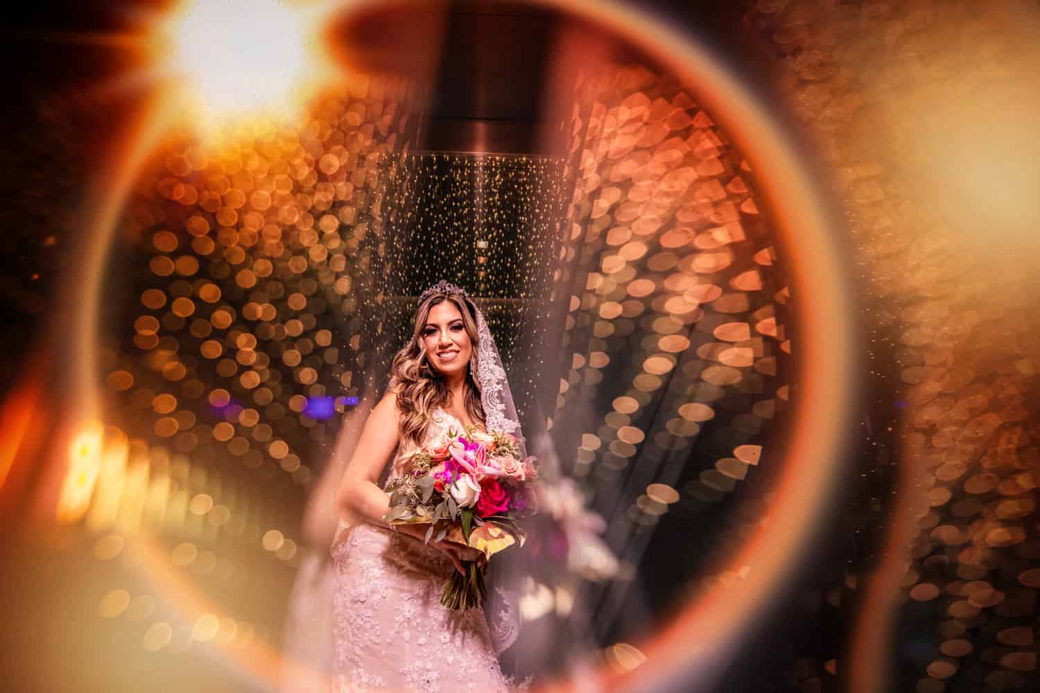 Bride with her bouquet framed through a wedding ring against golden bokeh