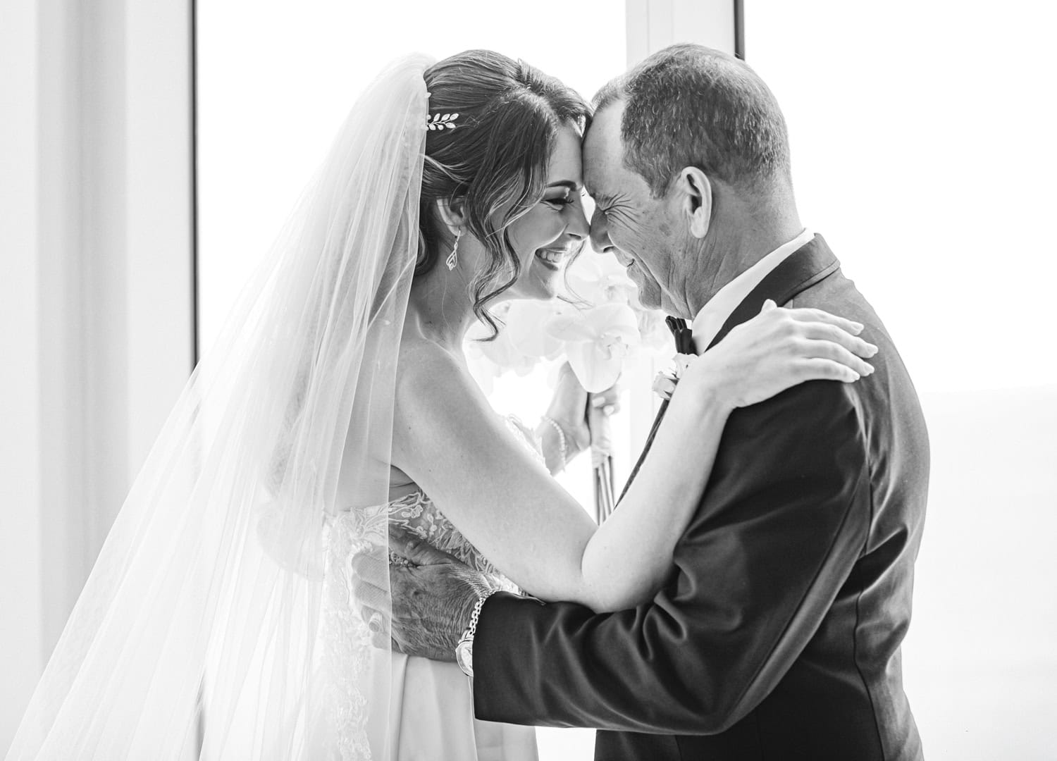 Bride and her father touching foreheads and smiling, in black and white