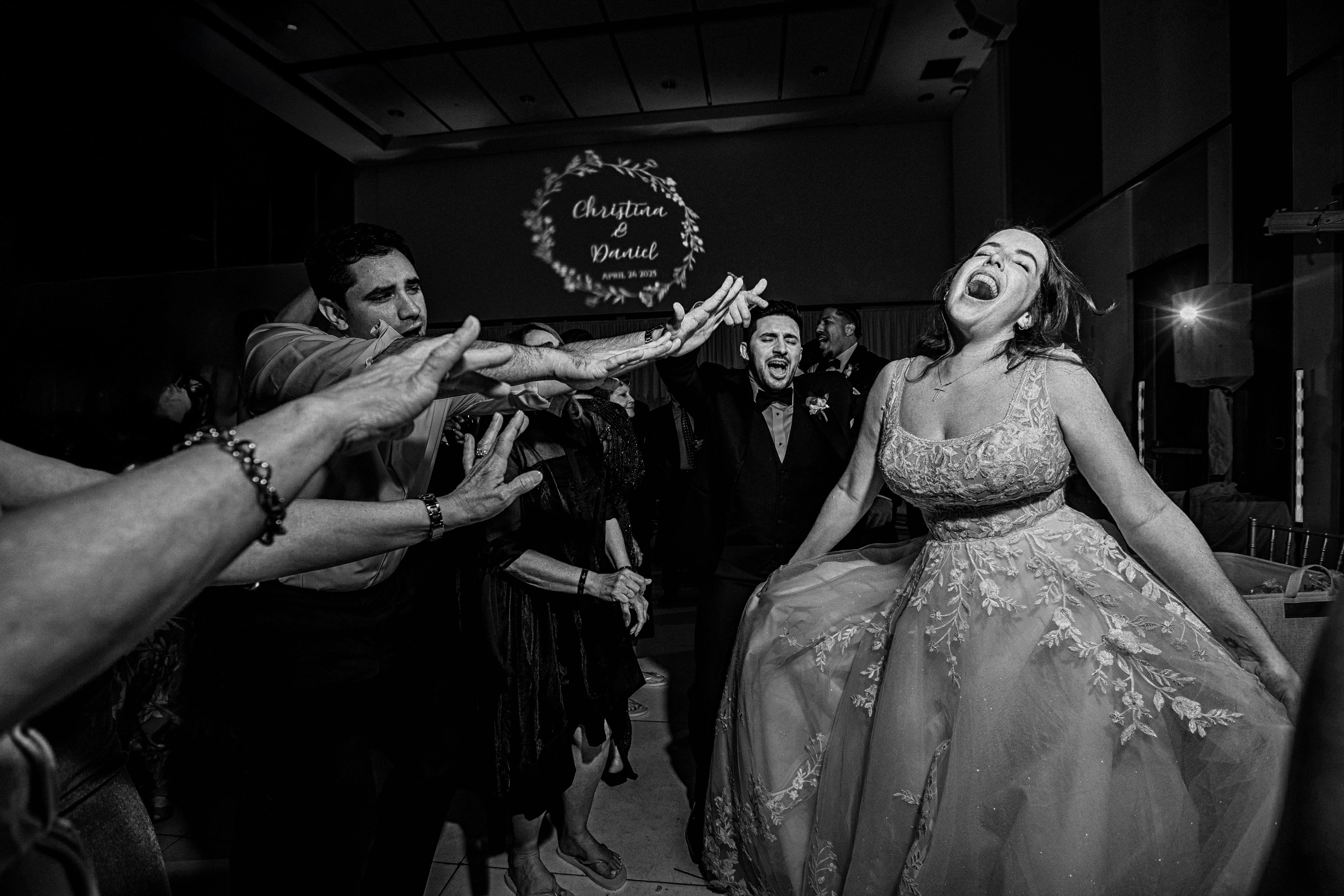 Bride and groom singing on the dance floor with their guests, black and white