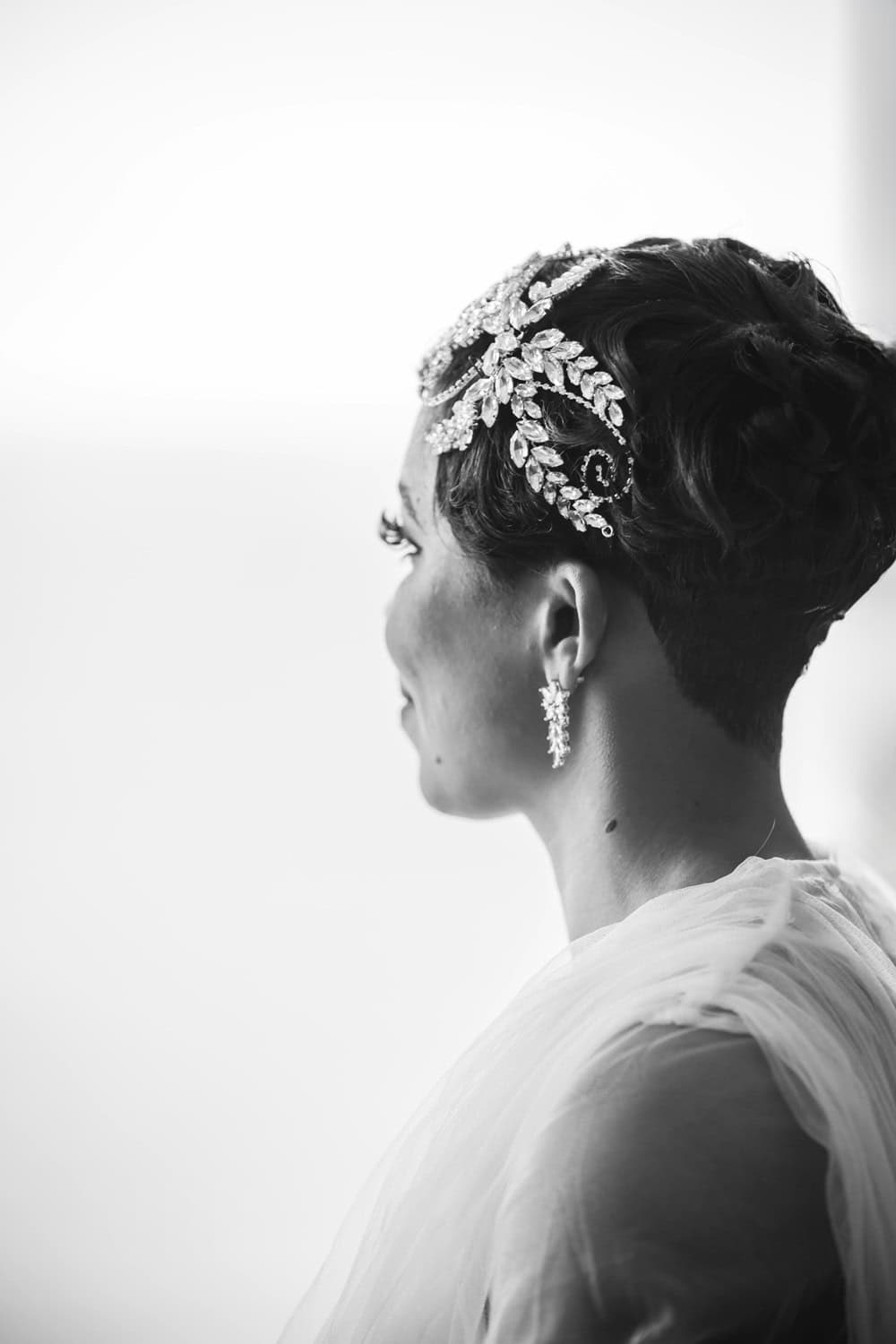 Bride in profile wearing a crystal leaf headpiece and drop earring, black and white