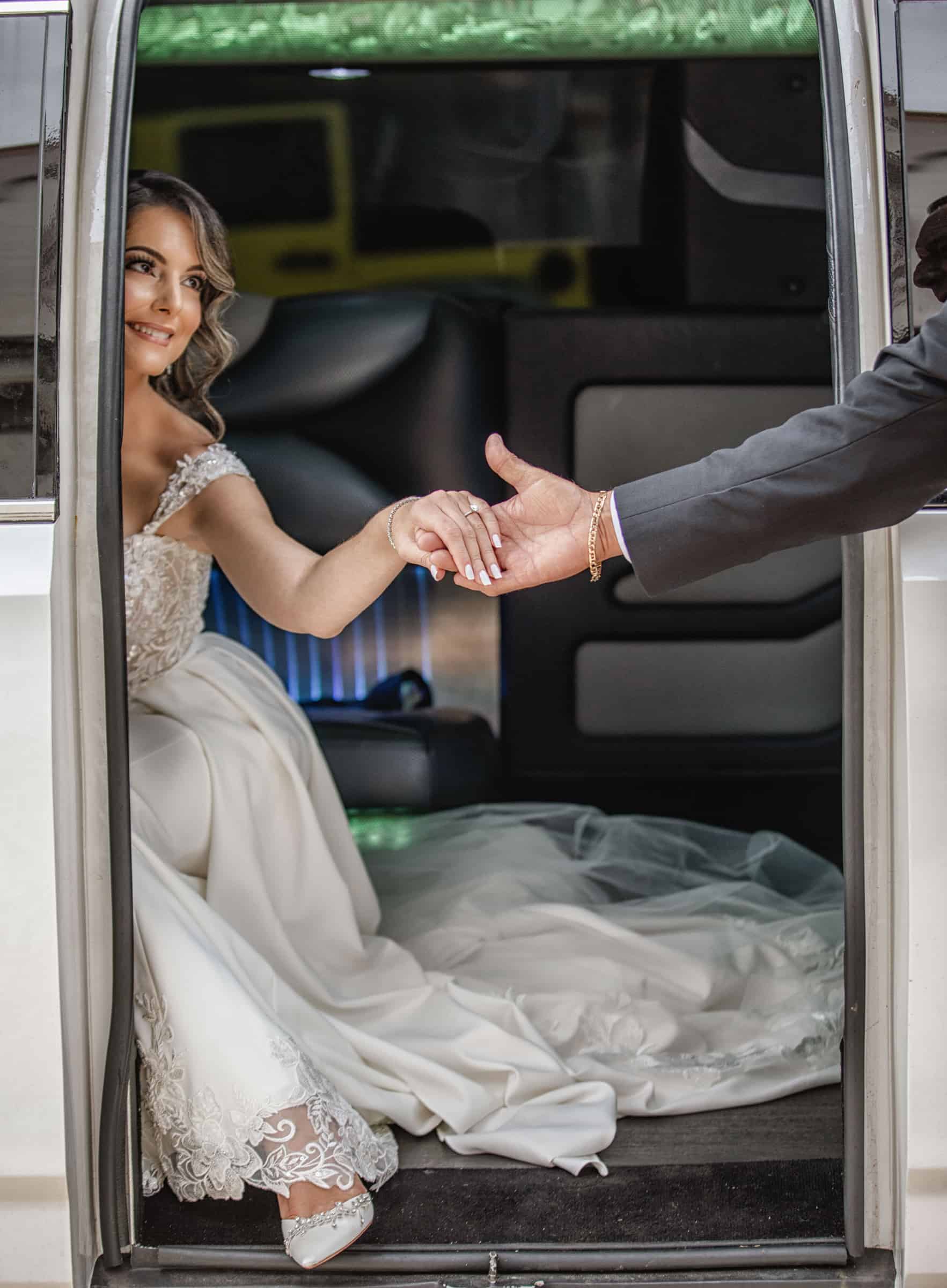 Bride reaching for the groom’s hand as she steps out of the limousine