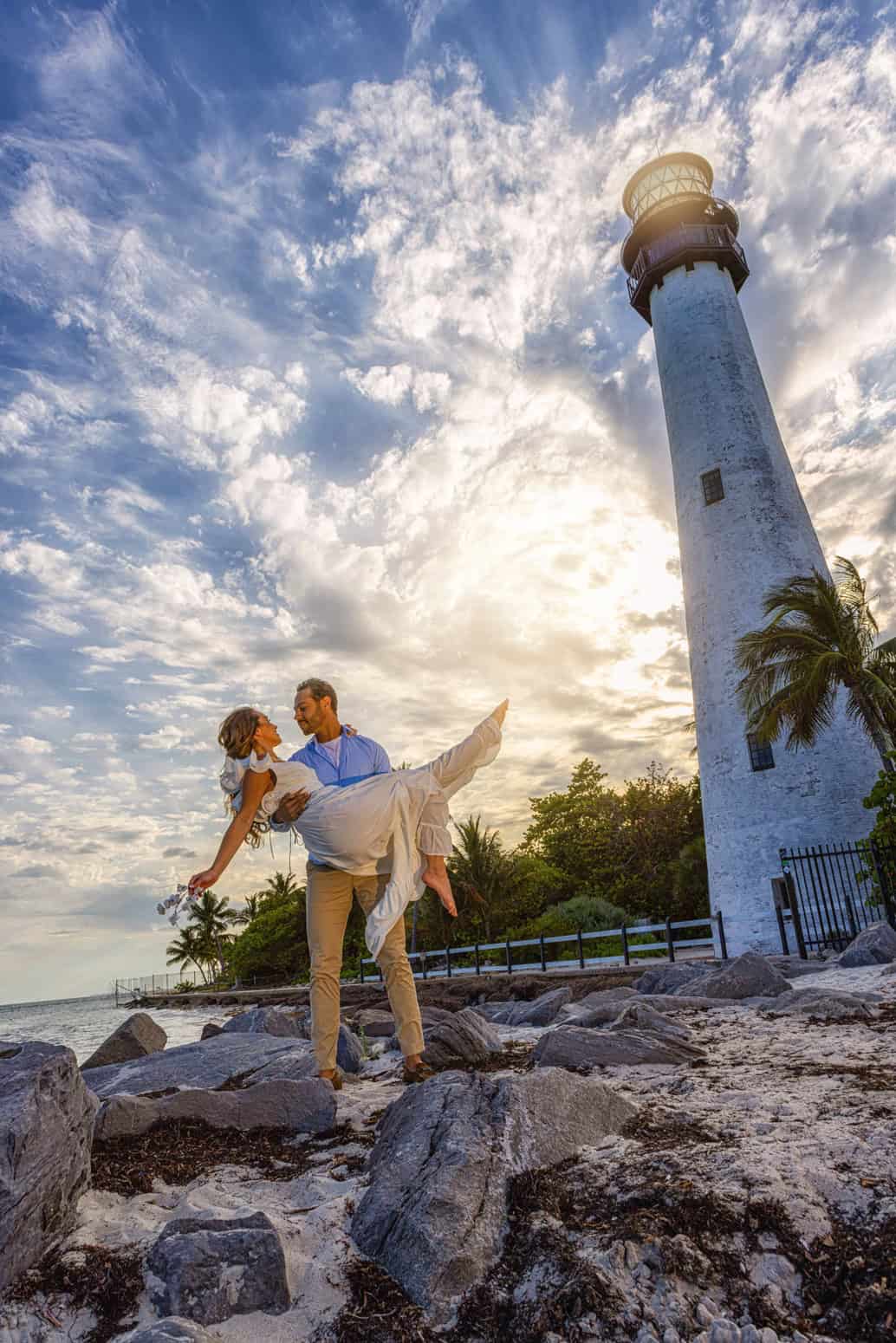 He lifts her in the air beneath the Cape Florida Lighthouse, Key Biscayne