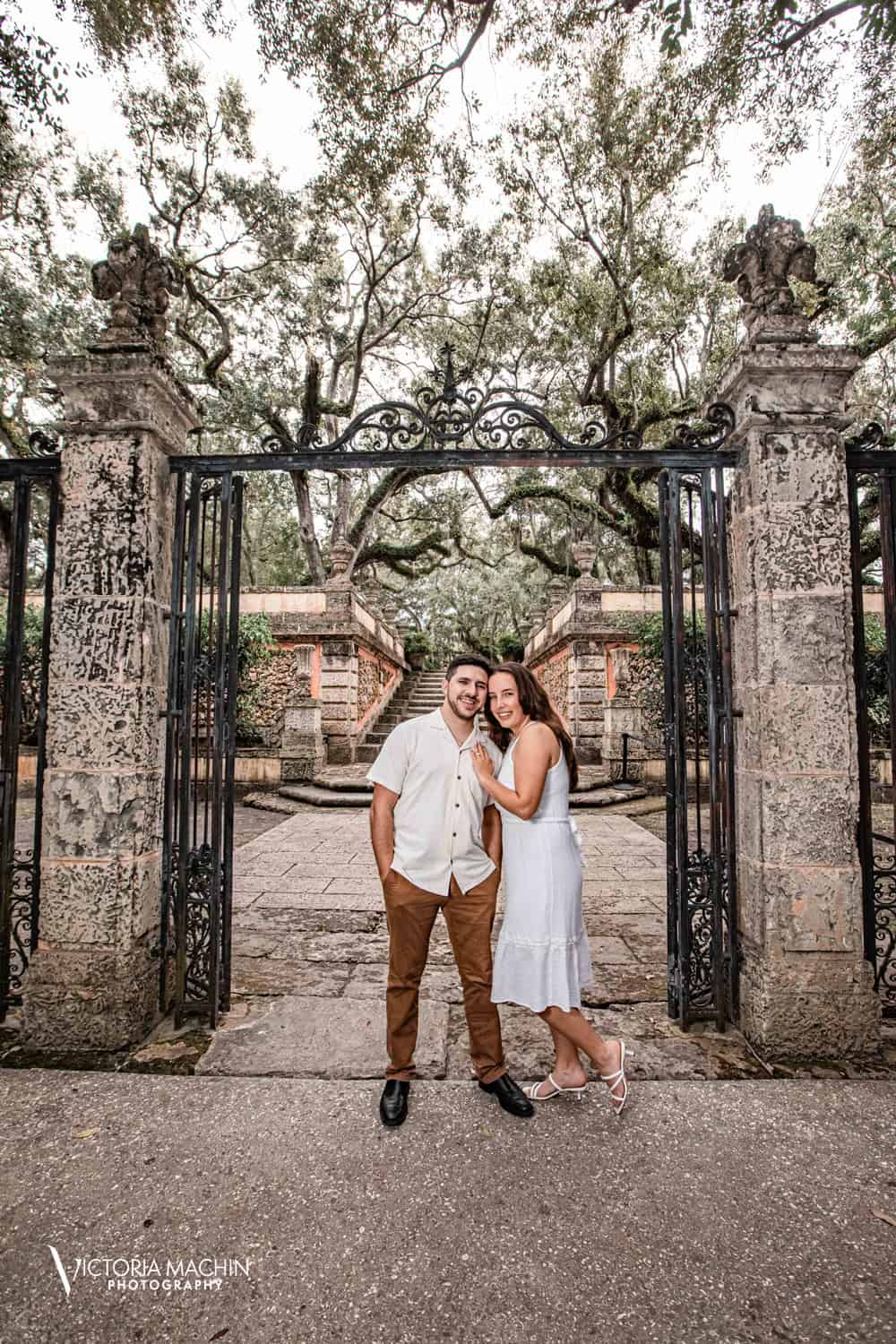 Couple beneath the wrought-iron gate and live oaks at Vizcaya