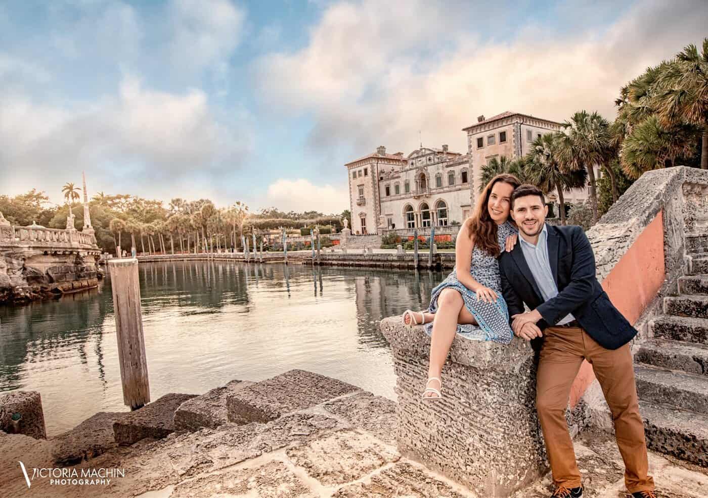 Engaged couple on the coral stone seawall with the Vizcaya mansion behind them