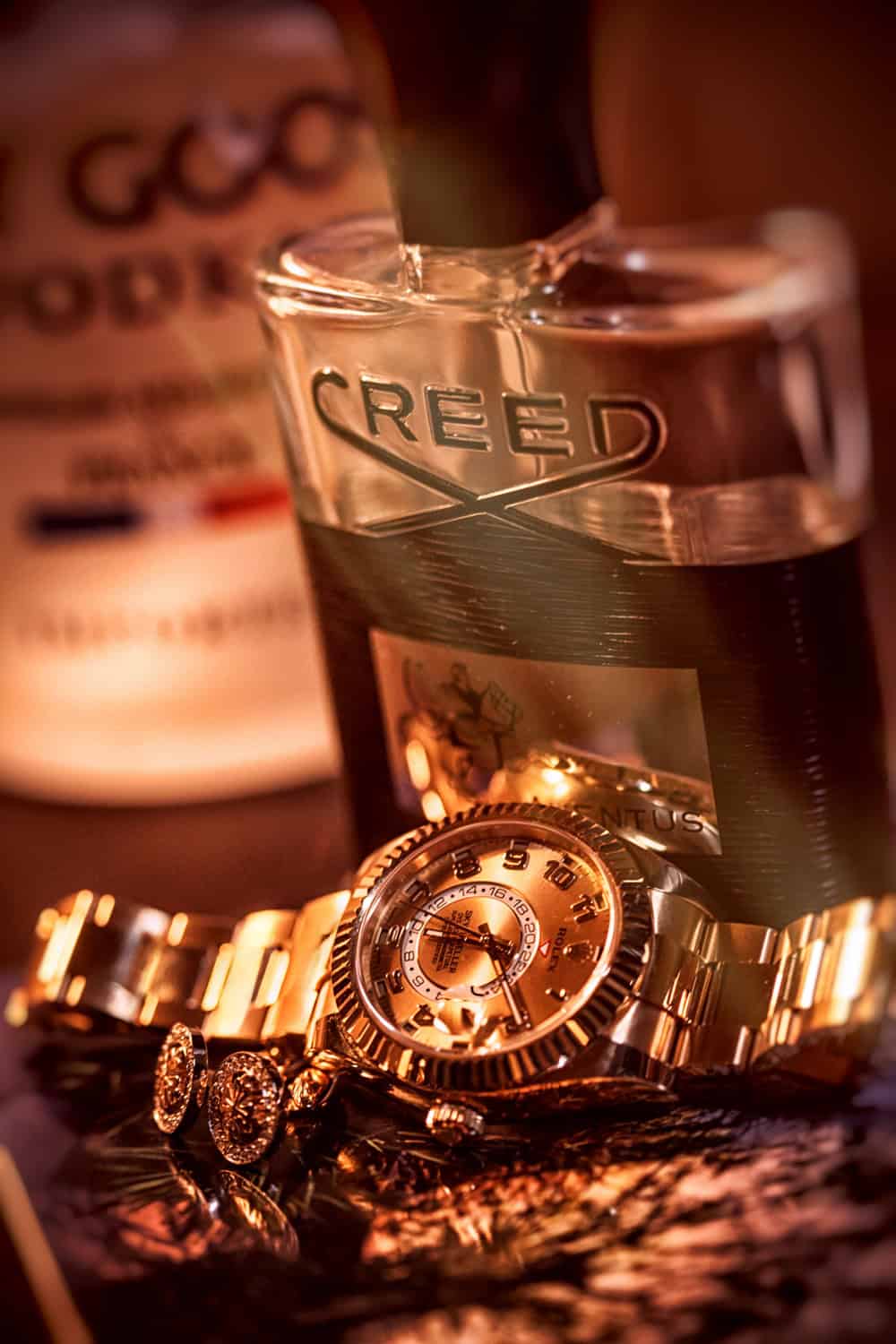 Groom details: gold Rolex, cufflinks and Creed cologne in warm light