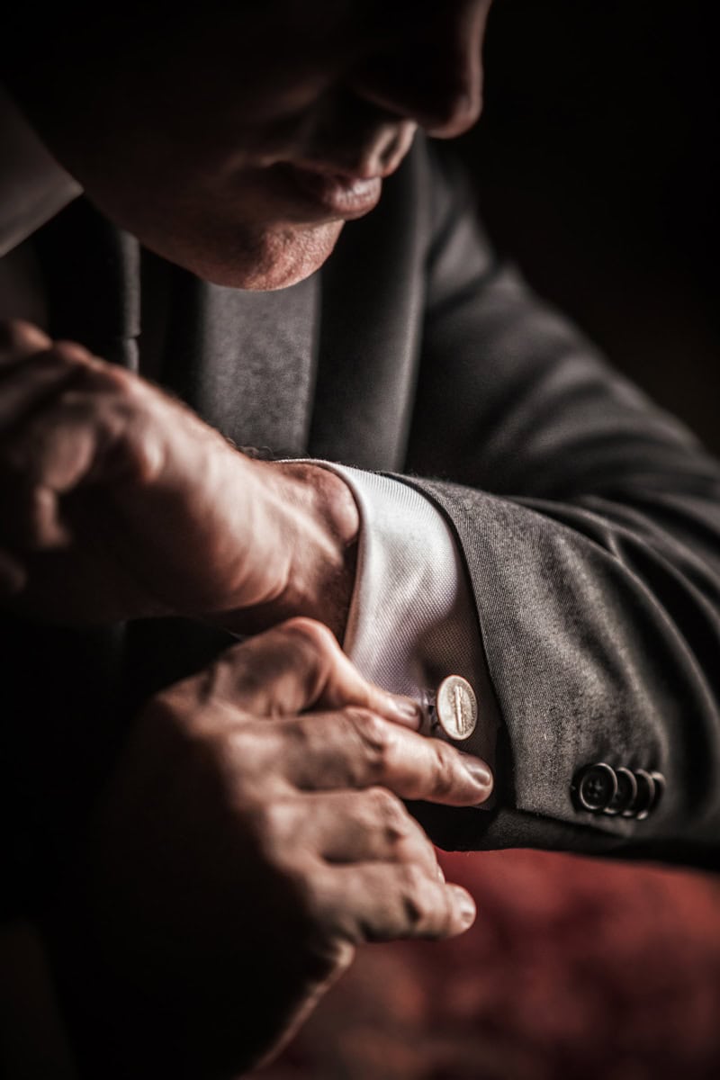Groom fastening a cufflink in dramatic low light