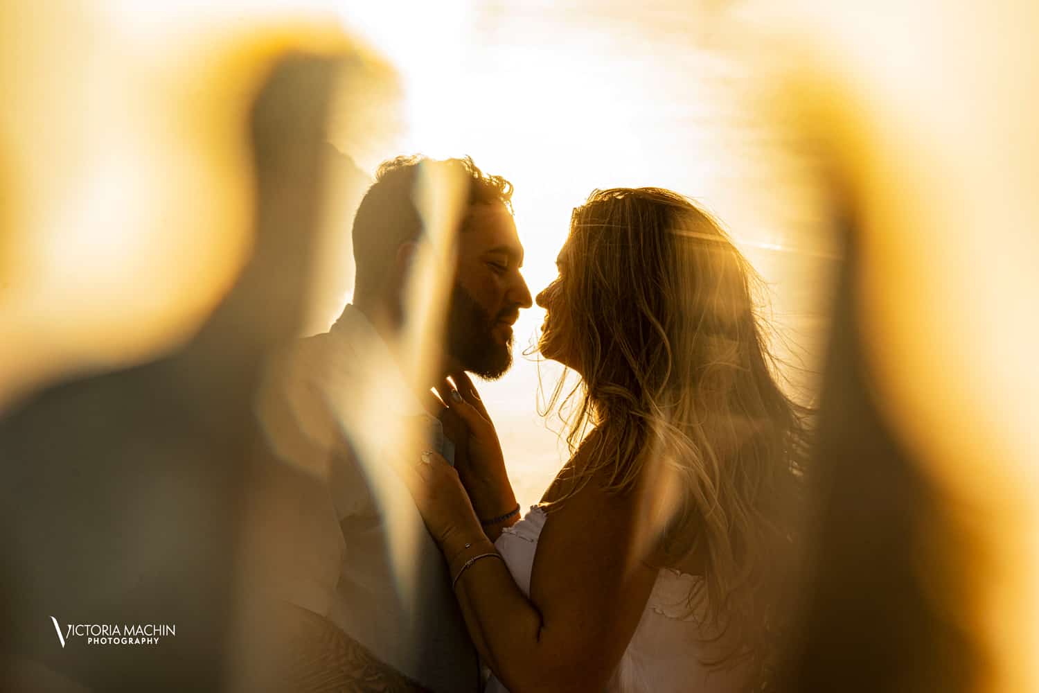 Newly engaged couple nose to nose in golden backlight