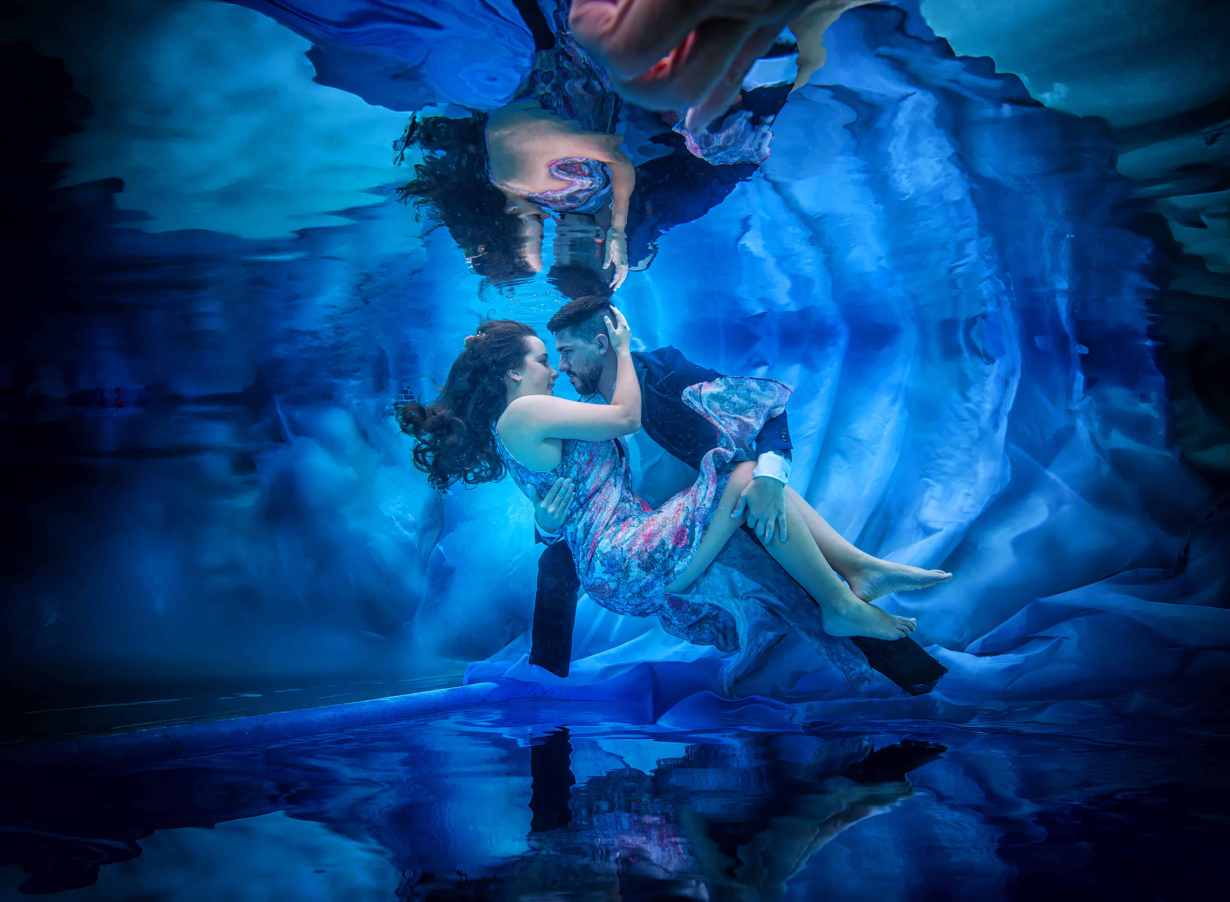 Engaged couple embracing nose to nose in a glowing blue underwater scene