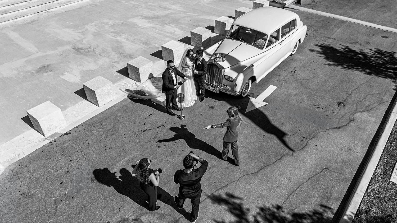 Aerial view of Victoria Machin directing a bride and groom beside a vintage Rolls-Royce