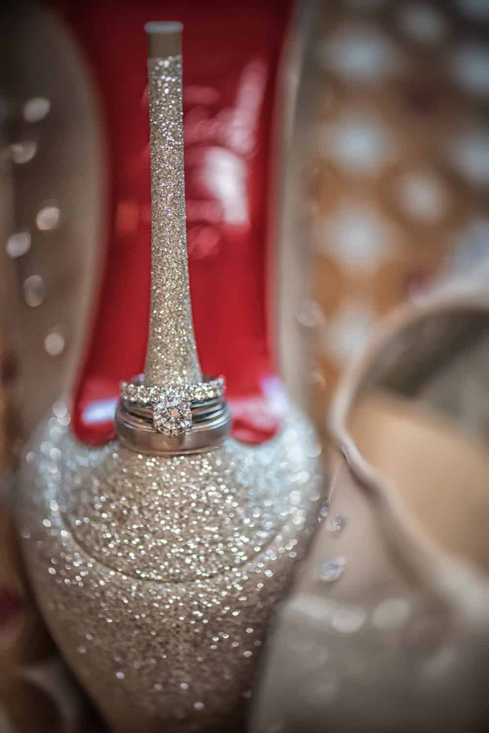 Wedding rings stacked on the heel of a glitter Louboutin with red sole